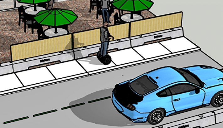 A man rides a Segway on a sidewalk next to a blue car parked on the street; nearby, outdoor tables with green umbrellas are set up behind a wooden fence.